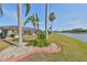 Manicured backyard with lush grass, tropical plants, and decorative rocks offers a serene view of the lake at 1123 Signature Dr, Sun City Center, FL 33573