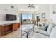 Comfortable living room featuring a large TV, plush seating, and access to a private balcony at 11605 Gulf Blvd # 404, Treasure Island, FL 33706