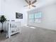 Bright Bedroom with ceiling fan, white walls, neutral carpet, white crib, and a window with outdoor views at 11828 Cara Field Ave, Riverview, FL 33579