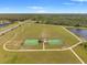 An aerial view of community sports courts in a large green space with walking paths and a lake at 13538 Willow Bluestar Loop, Riverview, FL 33579
