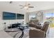 Comfortable living room with sliding doors, dual TVs, a ceiling fan, and plush seating at 13538 Willow Bluestar Loop, Riverview, FL 33579
