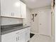 Mud room with granite countertops, white cabinets, gray tile flooring, and access to multiple doors at 13538 Willow Bluestar Loop, Riverview, FL 33579