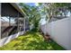 Enclosed backyard featuring a screened patio, lush lawn, privacy fence, and potted plants adding to the outdoor charm at 14916 Rocky Ledge Dr, Tampa, FL 33625