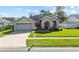 Charming one-story home with a two-car garage, arched entryway with red door, and well-manicured lawn on a sunny day at 14916 Rocky Ledge Dr, Tampa, FL 33625