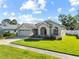 Inviting one-story home featuring a two-car garage, arched entryway, well-kept lawn and garden, and a sunny sky at 14916 Rocky Ledge Dr, Tampa, FL 33625