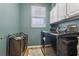 Clean laundry room with black appliances, white cabinets, and a natural wood floor at 16242 Rambling Rd, Odessa, FL 33556