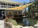 Relaxing backyard features a pond, lush landscaping, deck with outdoor seating and shade sail at 2005 Jackson N St, St Petersburg, FL 33704