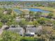 Scenic aerial view of a neighborhood with lush green trees, a serene pond, and well-maintained houses at 2009 Halidom Way, Sun City Center, FL 33573