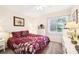 Bright bedroom featuring a burgundy floral comforter set and a large window at 2009 Halidom Way, Sun City Center, FL 33573
