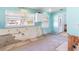 Kitchen with aqua walls and damaged trim with tile flooring and white cabinets at 311 Ravenna N St, Nokomis, FL 34275