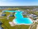 Community aerial view with a lagoon, sandy beaches and a clubhouse offering resort-style living at its finest at 31399 Penny Surf Loop, Wesley Chapel, FL 33545