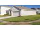 Well-maintained single-story home with a neutral-colored exterior, a two-car garage, and green lawn at 31399 Penny Surf Loop, Wesley Chapel, FL 33545