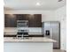 View of the kitchen featuring a stainless steel refrigerator, granite countertops, and dark wood cabinets at 31399 Penny Surf Loop, Wesley Chapel, FL 33545