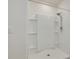 Bright, white shower with a modern shower head, built-in shelving, and sleek tile work at 31399 Penny Surf Loop, Wesley Chapel, FL 33545