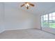 Carpeted bedroom is spacious and well lit with a ceiling fan and large window at 34907 Double Eagle Ct, Zephyrhills, FL 33541
