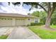 Charming home featuring a two-car garage, well-manicured lawn, and a large shade tree at 34907 Double Eagle Ct, Zephyrhills, FL 33541