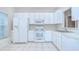 Bright kitchen with white appliances, cabinetry, and tile floors, lit by a window at 34907 Double Eagle Ct, Zephyrhills, FL 33541