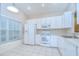 Well-lit kitchen featuring white appliances, cabinetry, and tile flooring near a window at 34907 Double Eagle Ct, Zephyrhills, FL 33541