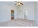 Spacious main bedroom featuring neutral carpeting, ceiling fan, and ensuite bathroom with arched doorway at 34907 Double Eagle Ct, Zephyrhills, FL 33541