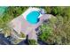 Aerial view of a private pool surrounded by lush greenery and the unique architectural design of the home at 34907 Double Eagle Ct, Zephyrhills, FL 33541