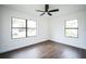 Sunny bedroom featuring new wood-look flooring, a ceiling fan, and two large windows at 3710 W Griflow St, Tampa, FL 33629