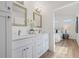 Bathroom featuring double sinks, white cabinets, framed mirrors and view of the bedroom at 3860 Whiting Se Dr, St Petersburg, FL 33705