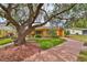 Charming single-story home featuring a well-maintained lawn, mature landscaping, and a welcoming orange front door at 401 Dorchester Pl # 69, Sun City Center, FL 33573