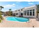The backyard has an in-ground pool with brick patio and views of a two-story home at 517 Belle Isle Ave, Belleair Beach, FL 33786