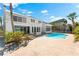 Rear exterior of two-story house with an in-ground pool, brick patio, and lush tropical landscaping at 517 Belle Isle Ave, Belleair Beach, FL 33786