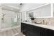 Bright bathroom with double sink vanity, decorative tile, and glass enclosed shower with gold fixtures at 517 Belle Isle Ave, Belleair Beach, FL 33786