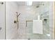 Shower with glass doors, gold hardware, and white marble-look tiling with built-in shelving at 517 Belle Isle Ave, Belleair Beach, FL 33786