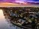 Stunning waterfront home featuring a private dock, lush landscaping, and a pool, set against a backdrop of a vibrant sunset sky at 520 Belle Isle Ave, Belleair Beach, FL 33786
