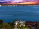 Gorgeous waterfront property boasting manicured lawns and mature palm trees, with expansive water views and a city skyline beyond at 520 Belle Isle Ave, Belleair Beach, FL 33786