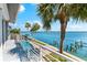 Scenic view from the balcony overlooking the pool, palm trees, and the serene blue water at 520 Belle Isle Ave, Belleair Beach, FL 33786