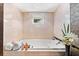 Large soaking tub with tile surround and a window to the outdoors at 520 Belle Isle Ave, Belleair Beach, FL 33786