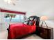 Bedroom featuring waterfront views, red bedding, and a dark wood nightstand and bed frame at 520 Belle Isle Ave, Belleair Beach, FL 33786