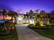 Expansive waterfront home featuring a lush, landscaped yard with palm trees and an arched entry, perfect for luxurious living at 520 Belle Isle Ave, Belleair Beach, FL 33786