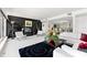 Spacious living room with modern furnishings, black accent wall with fireplace, and expansive windows with water views at 520 Belle Isle Ave, Belleair Beach, FL 33786