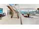 Bright living room with a curved staircase, white sofa, open layout, and scenic water views through large windows at 520 Belle Isle Ave, Belleair Beach, FL 33786