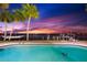 Beautifully lit pool area with palm trees and a hammock, offering a relaxing waterfront experience at night at 520 Belle Isle Ave, Belleair Beach, FL 33786