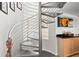 Unique, modern metal spiral staircase by a bar area, lit by a glass block window, creating an airy space at 520 Belle Isle Ave, Belleair Beach, FL 33786
