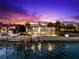 Luxurious waterfront home with a private dock, a stunning pool, and beautifully landscaped grounds at dusk at 520 Belle Isle Ave, Belleair Beach, FL 33786