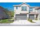 A modern townhouse with a gray garage door, complemented by a well-manicured lawn and blue sky at 6867 Citrus Creek Ln, Tampa, FL 33625