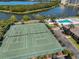 Aerial view showcasing tennis courts, a swimming pool, and lake access in the community at 10038 62Nd N Ter # 21, St Petersburg, FL 33708