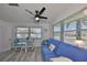 Bright living room with modern ceiling fan, blue sofa, and view through large windows at 10038 62Nd N Ter # 21, St Petersburg, FL 33708