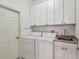 Functional laundry room equipped with a washer, dryer, sink, and ample cabinet space at 14605 Chatsworth Manor Cir, Tampa, FL 33626