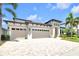 Beautiful exterior elevation with a large driveway, three car garage, and tropical landscaping at 14610 Red Castle Ave, Lithia, FL 33547