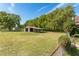 Spacious backyard with mature trees and a outbuilding offering space for outdoor activities and potential storage at 1501 W Trapnell Rd, Plant City, FL 33566