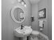 Stylish half-bathroom featuring a white pedestal sink, oval mirror, and elegant black and white patterned flooring at 15618 Shoal Creek Pl, Odessa, FL 33556