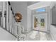 Elegant foyer with white staircase, glass front door and sunburst mirror at 15618 Shoal Creek Pl, Odessa, FL 33556